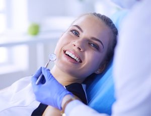 Woman smiling while receiving a checkup 