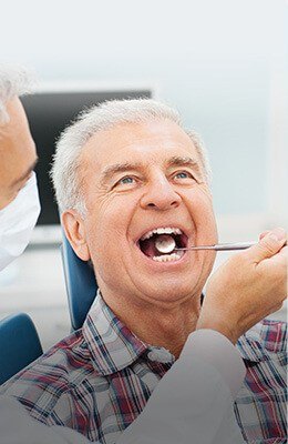 Dentist performing dental exam on a senior man