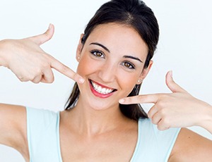 young woman pointing to her smile with white teeth 