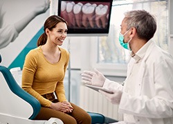 Dentist talking to smiling patient in treatment room