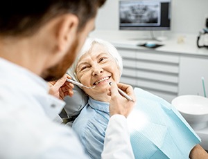 Older woman smiling while dentist checks her teeth