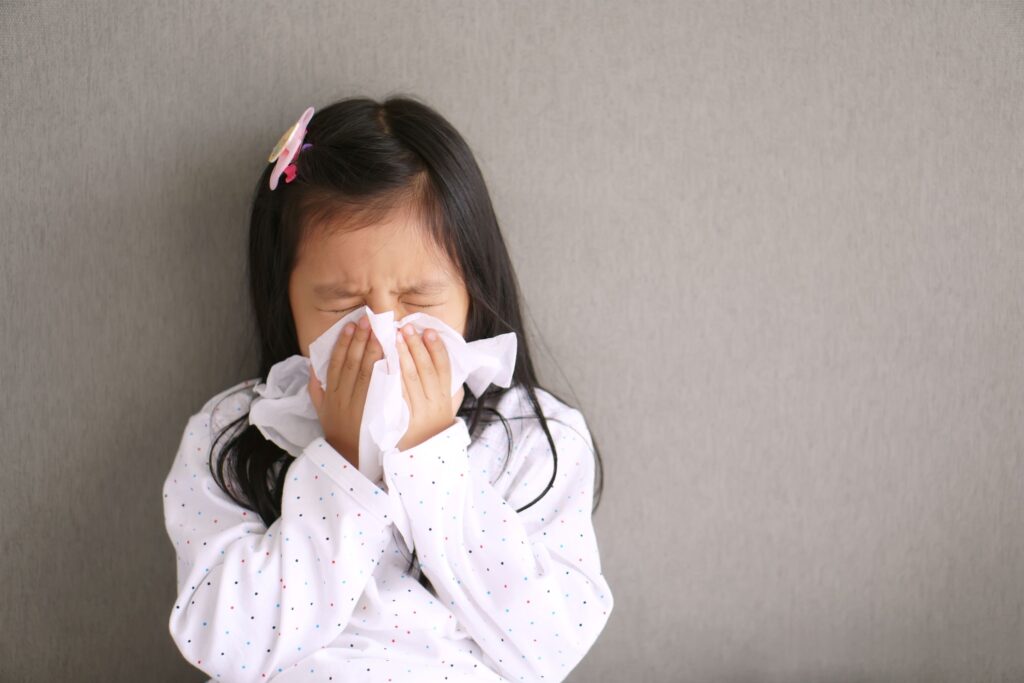 Little girl blowing nose into a tissue almost as big as her face